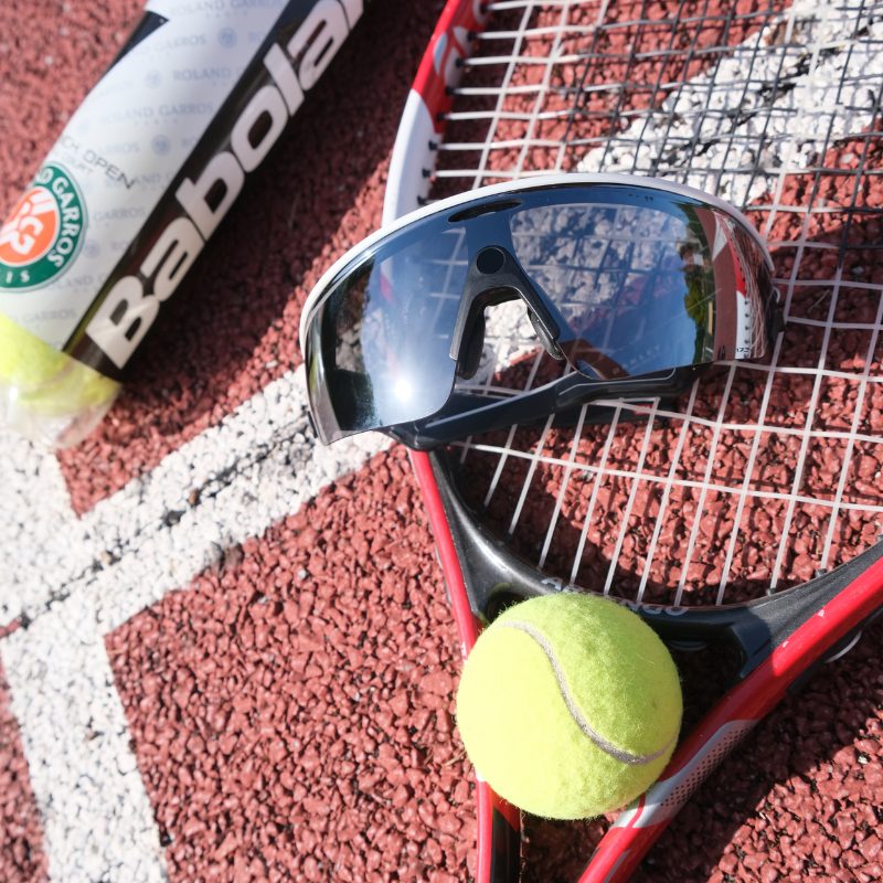Lunettes Oakley Meta Vanguard sur un court de tennis avec balle & raquette